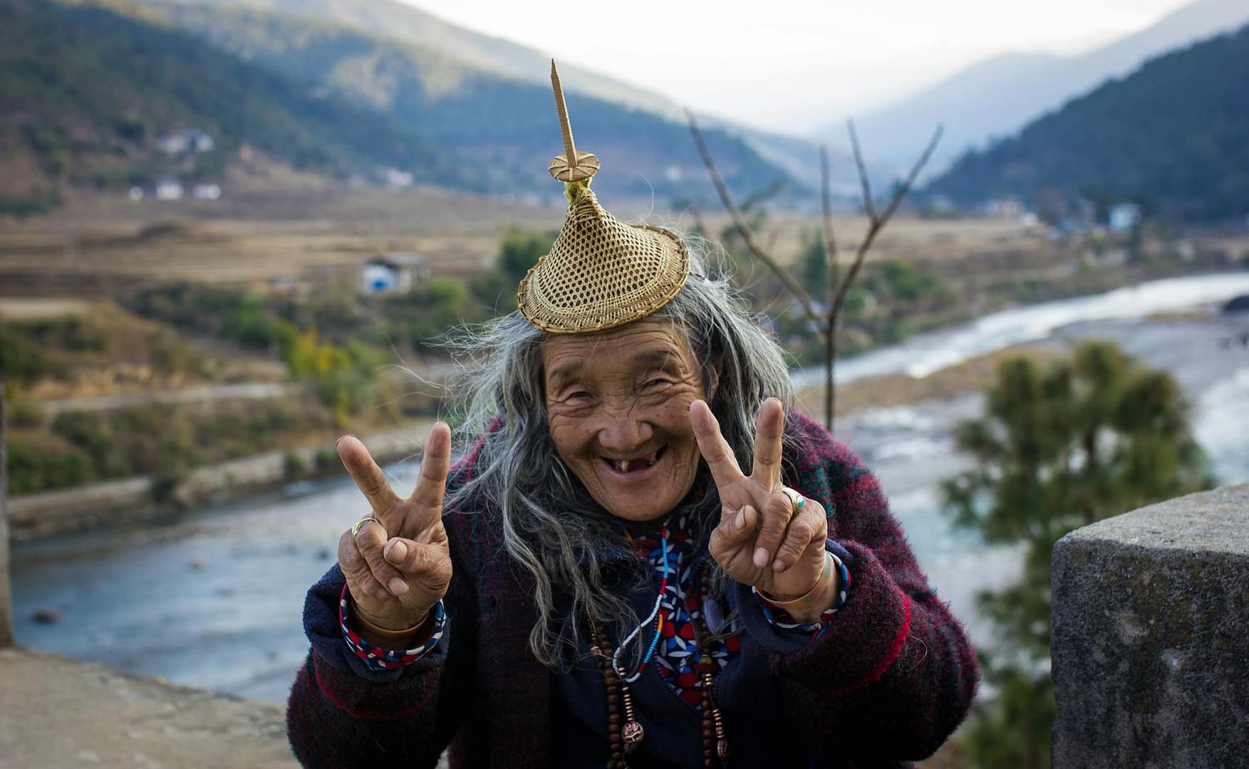 old ethnic woman showing v sign in countryside